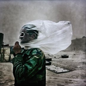 An Afghan soldier protects his face from a dust storm. Balazs Gardi / Basetrack.org, Creative Commons